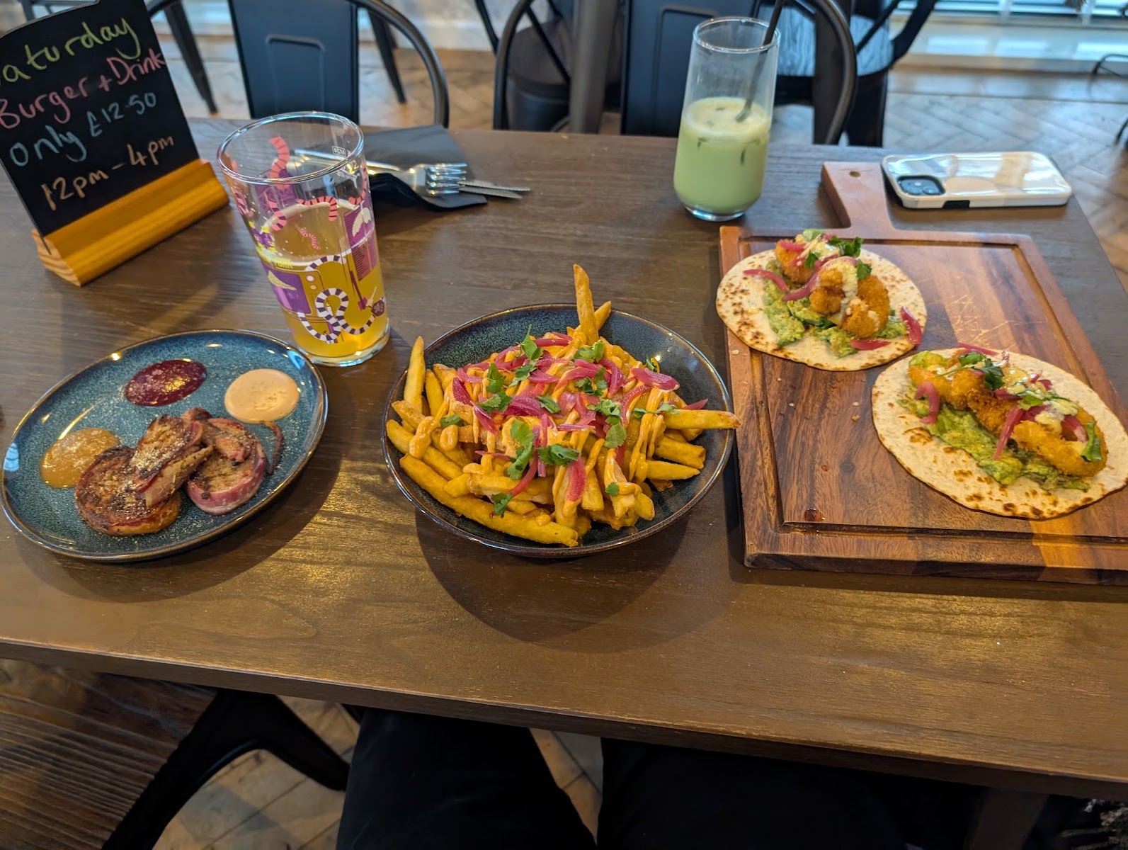 Casual dining table with burgers, loaded fries, tacos, and drinks